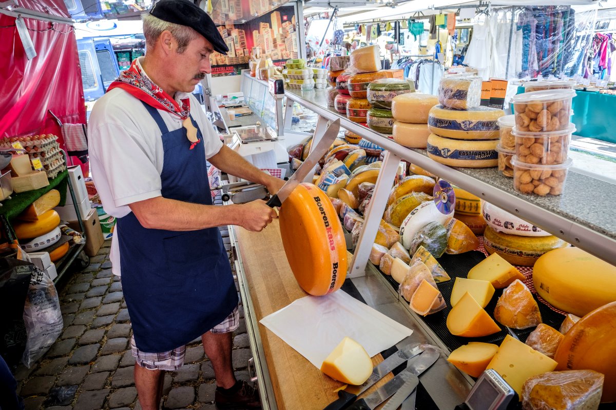 Leo Versluis in Franse look op de kaasmarkt van Gouda. Een kraam kost per dag 35 euro. Niet alleen verkoop van boerenkaas uit de regio, maar ook in beperkte mate Franse kazen en versnaperingen.