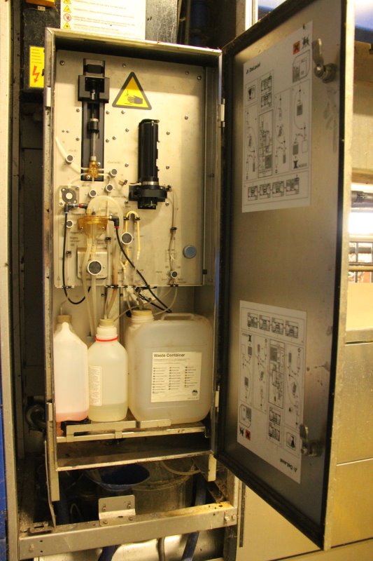 De ingenieuze machine OCC neemt een melkmonster, mengt dit met kleurreagens (linker can), en mengt deze in het glazen buisje (linksboven). De zwarte camera maakt een 'foto' van de melk en telt de cellen. De melk loopt weg de put in, met water en reinigingsmiddel wordt de installatie nagespoeld.